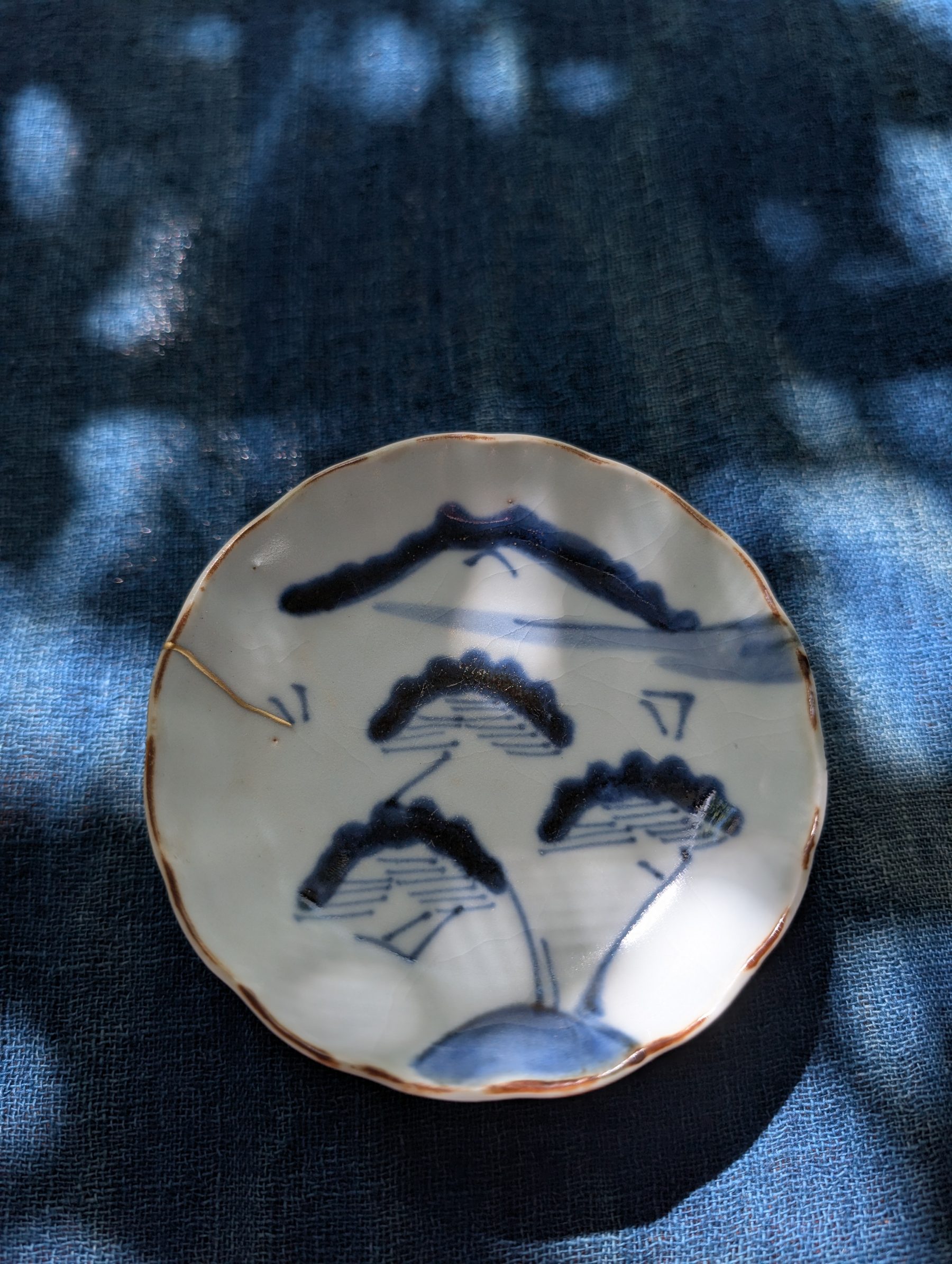 A finished dish with a gold seam on indigo cloth