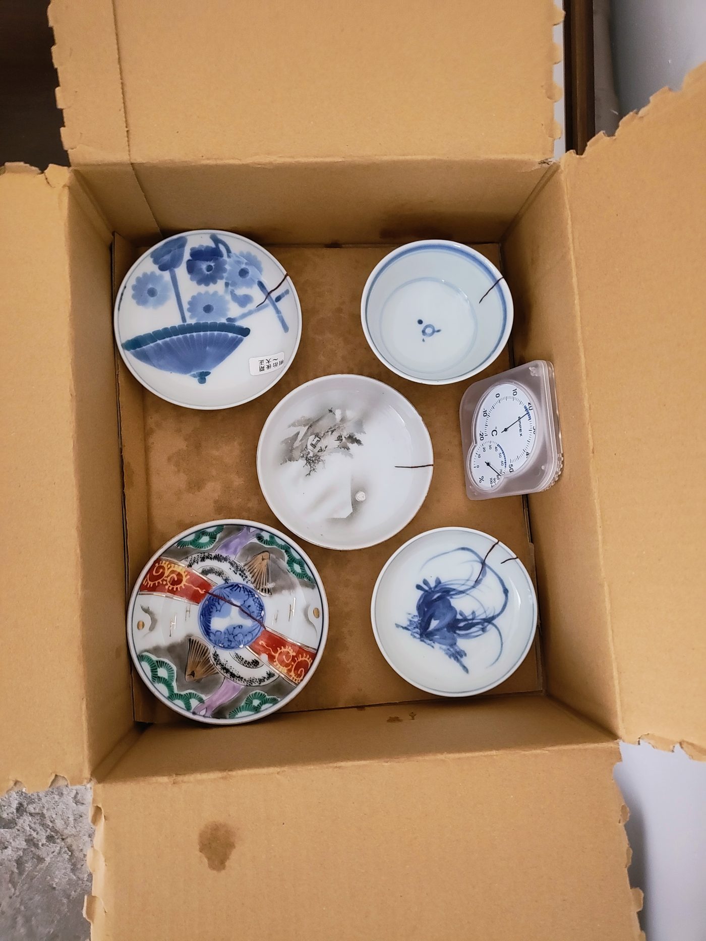 A box of antique dishes with repaired cracks, ready for the final gold step